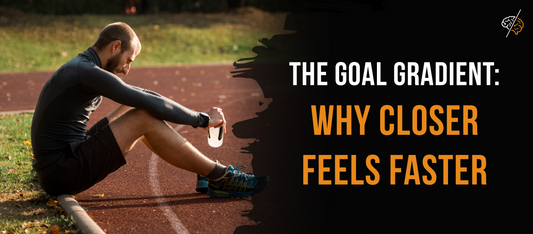 male runner in shorts and a long sleeve shirt shitting on the side of a running track looking down and tired holding a water bottle. The words "The goal gradient: Why Closer Feels Faster" are on the image